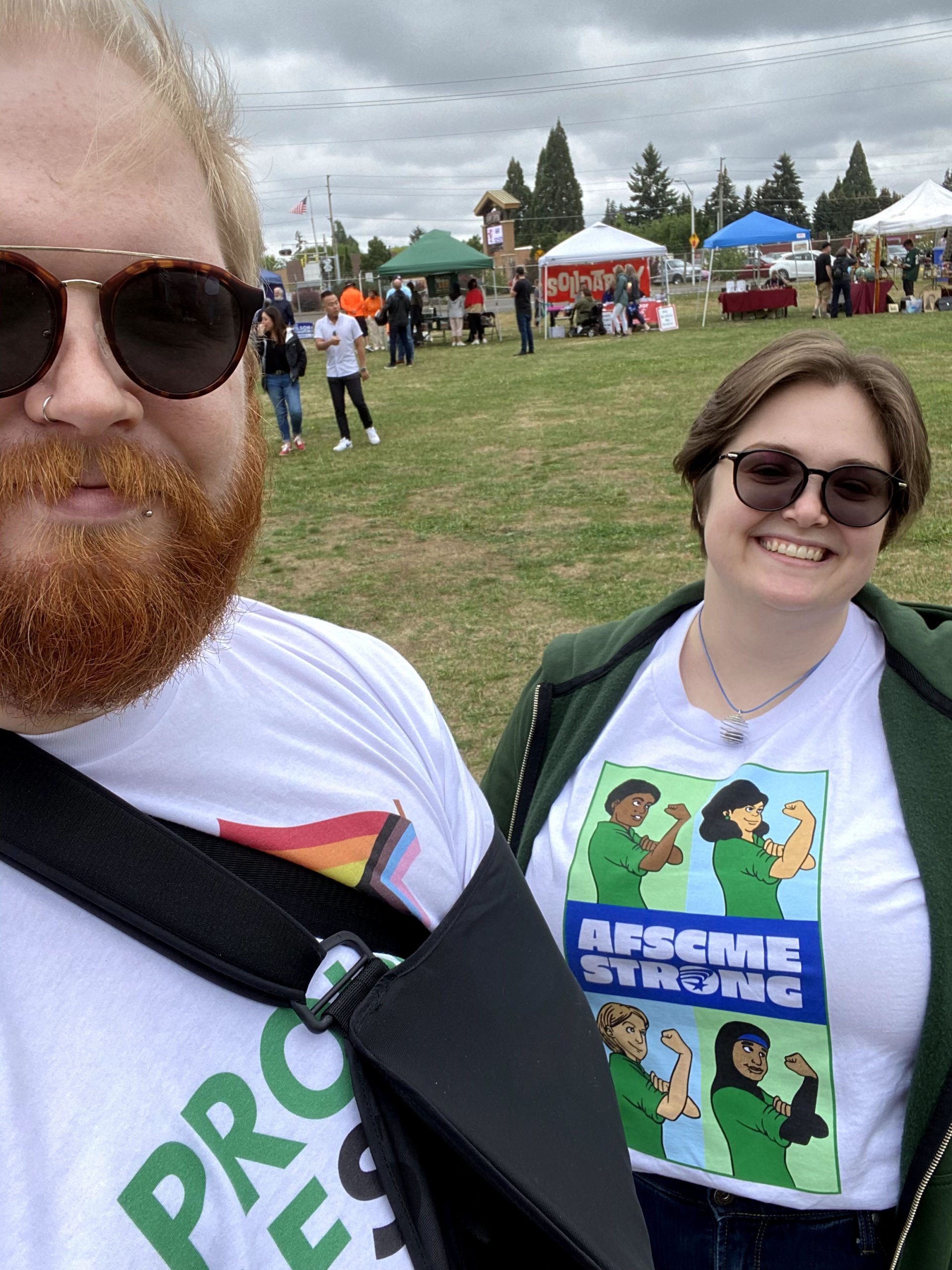 CG Brothers, a white nonbinary person with blonde hair and a red beard at a Labor Day Picnic with their fiancee